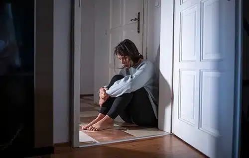 Depressed woman seated on the floor of her apartment