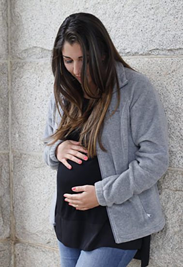 a pregnant Hispanic woman touching her belly and wondering about adoption