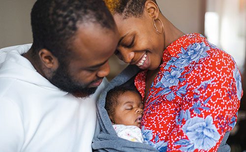 African American adoptive couple admiring their newborn baby