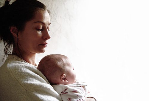 New adoptive mother holding her baby while suffering from post-adoption depression