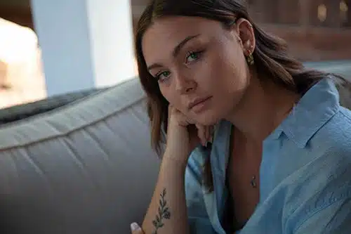 Young woman looking at the camera while  resting her head in her hand