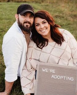 Hopeful adoptive parents Caleb and Rebecca hold an adoption letter board