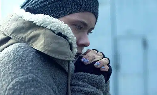 Pregnant and homeless woman trying to stay warm outside
