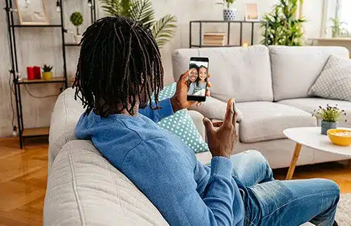 Birth father in his living room on a video call with his daughter and the adoptive family