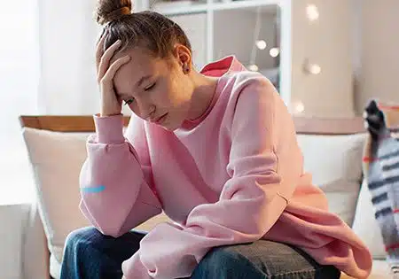 Depressed teen girl sitting on a couch at home