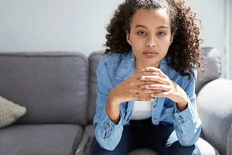Young woman seated on a sofa stares at the camera