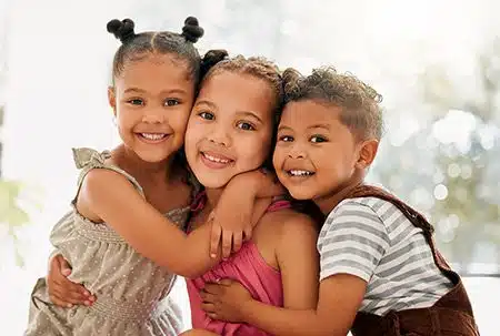 Two sisters and their brother hugging