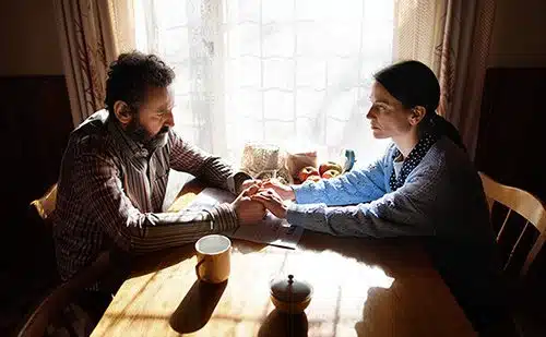 Husband and wife holding hands while having a serious talk at their kitchen table