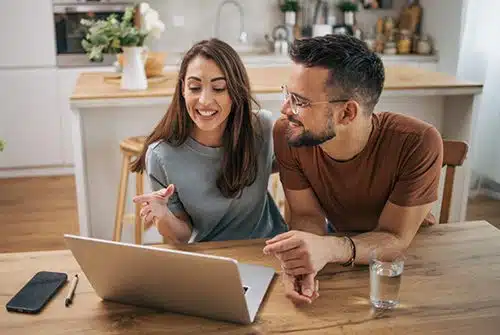 Couple using laptop computer in their kitchen to browse crowdfunding sites