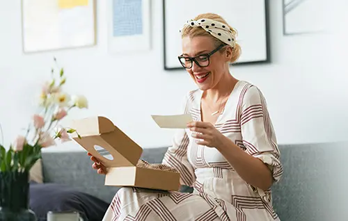 Happy adoptive mom in her living room reading a note from a gift 