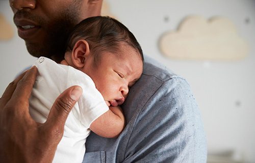 Adoptive father holding his newborn son is happy to share in infant care