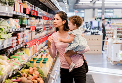 Young mother grocery shopping with her fussy toddler daughter