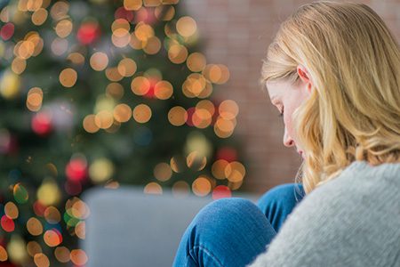 sad woman by Christmas tree