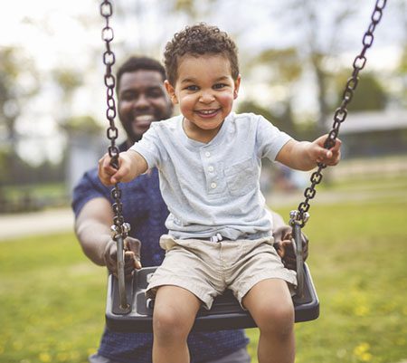 dad pushing boy on swing