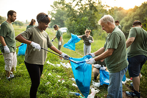 Multi-ethnic group of volunteers working together as a team while cleaning public park on a Make a Difference Day