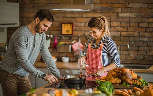 Happy couple cooking side dish for Thanksgiving dinner