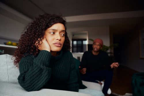 Woman seated in her living room, upset at her boyfriend