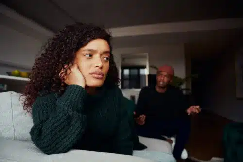Woman seated in her living room, upset at her boyfriend