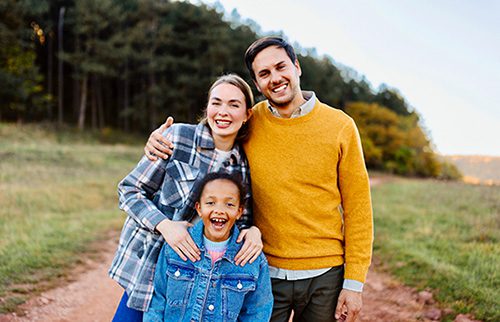 Adoptive mom and dad joyfully pose with their daughter