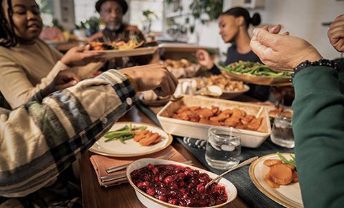 A Black family gathers together to cook and eat a Thanksgiving meal