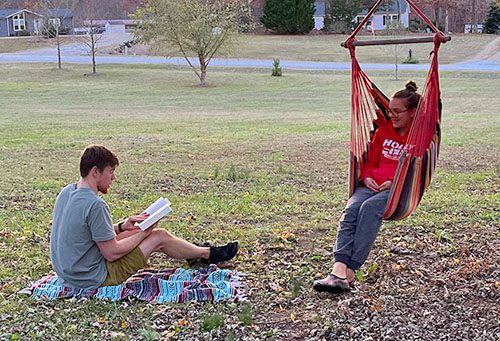 Blake reads to his wife Maggie while she sits in a hammock chair