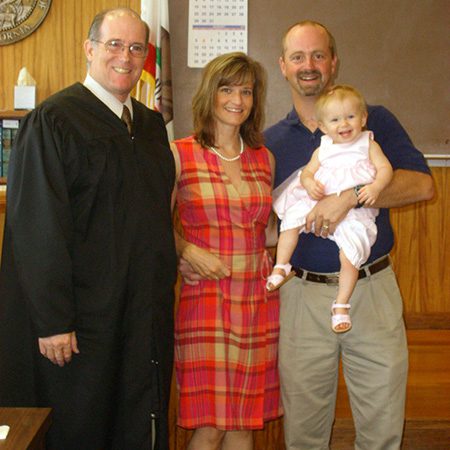 Adoptive couple with judge after adoption law finalization