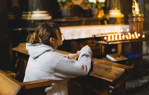Young Catholic woman praying alone in a church