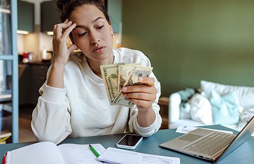 Worried young woman trying to pay her bills online at home