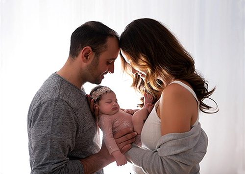 Lifetime adoptive parents Justino and Gina gaze lovingly at their infant daughter