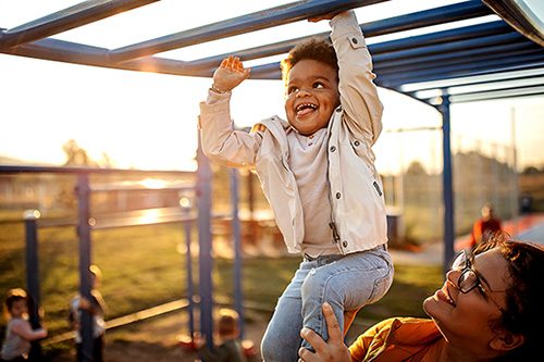 Preschool-age boy playing at a park with his mother