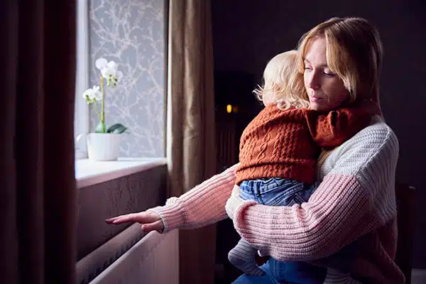 Mom with toddler son trying to keep warm by the radiator