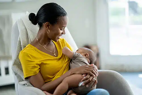 A new adoptive mother in her baby's nursery with the infant in her arms as she nurses him