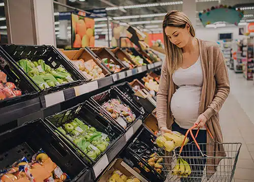 Pregnant woman shopping for groceries in the produce section