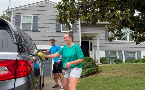 Bob and Emily having fun washing their car in their driveway