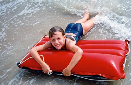 Emily having fun at the ocean as a child