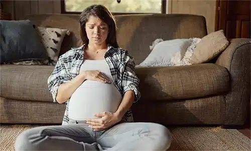 Distressed pregnant young woman in her living room