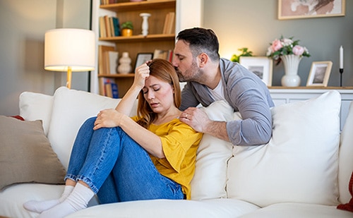Husband supporting his wife in their living room as she grieves on Mother's Day