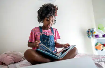 Little black girl looking at her adoption lifebook in her bedroom
