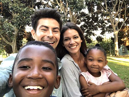 Family grown by adoption. Dad, mom and kids looking into camera.