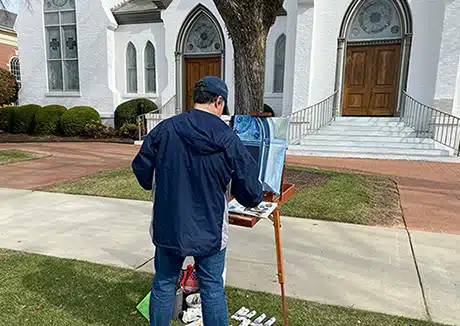 Hopeful adoptive dad Chad painting a church door al fresco