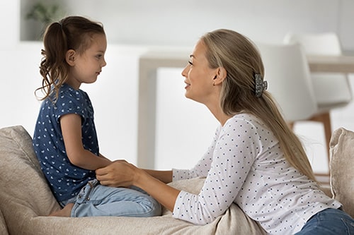 Smiling adoptive mother involved in a sincere conversation with her daughter