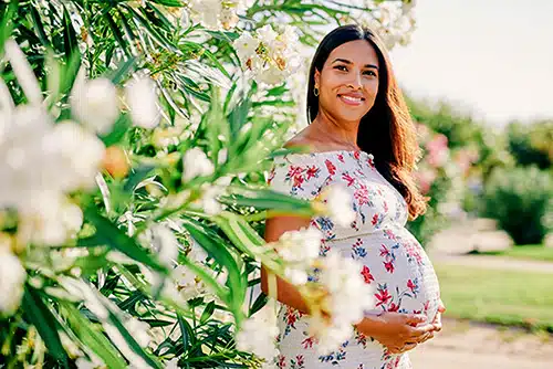 Latin pregnant woman posing outside at the park on a sunny day