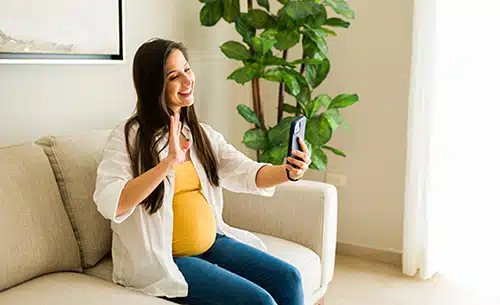 Happy expectant mom waving during a FaceTime call with hopeful adoptive parents