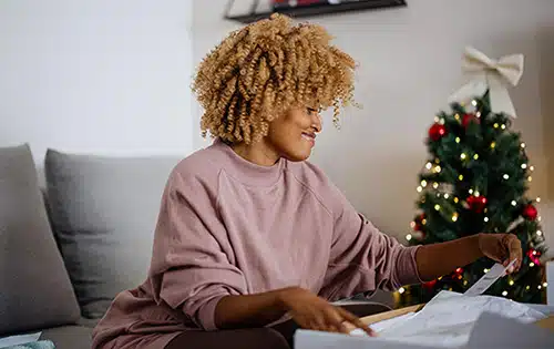 Smiling woman unpacking a gift parcel at home