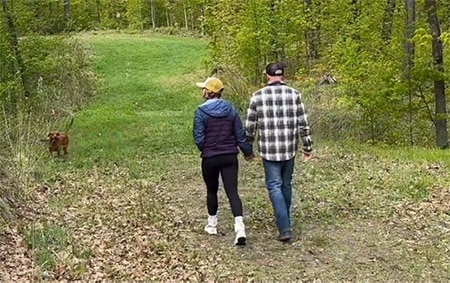 Taylor and Chad holding hands while hiking with their dog