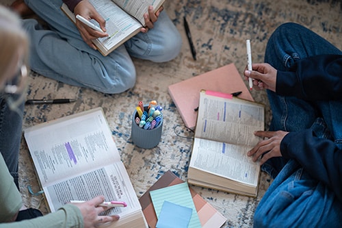 Bible study group seated on the floor with highlighters and books studying Bible verses about adoption