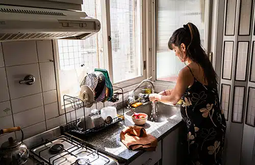 Single and pregnant woman washing fruit in her kitchen sink