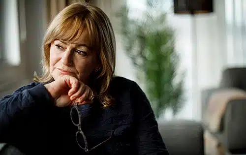 Sad senior woman sitting on her sofa at home