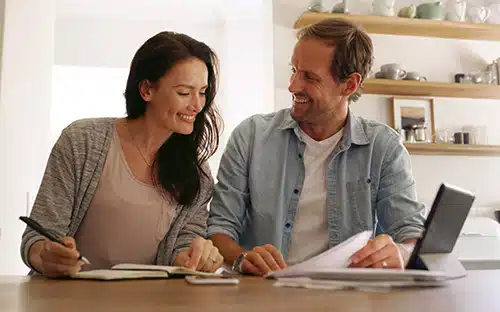 Husband and wife seated in their kitchen looking into financial assistance for adoption at the counter