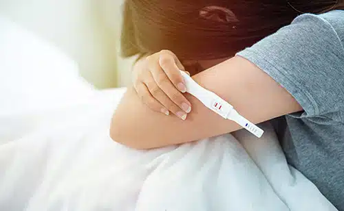 Young anxious woman with a positive pregnancy test in her hand
